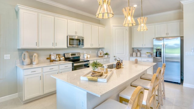 kitchen with a kitchen breakfast bar, stainless steel appliances, decorative light fixtures, white cabinetry, and an island with sink