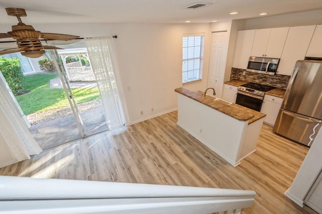 kitchen with backsplash, white cabinets, sink, light hardwood / wood-style floors, and stainless steel appliances