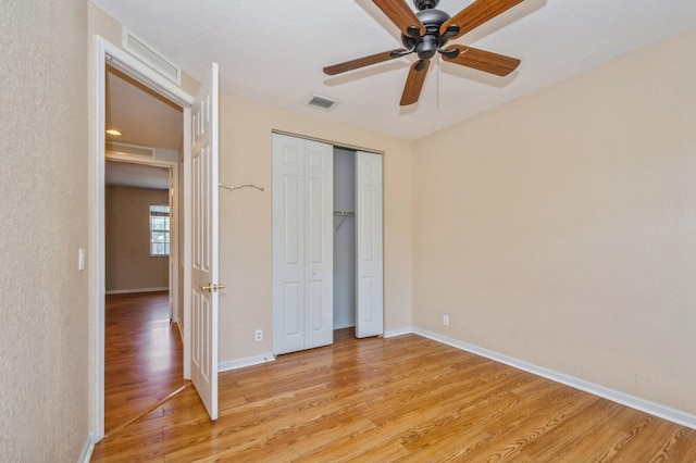 unfurnished bedroom with ceiling fan, light hardwood / wood-style floors, and a closet