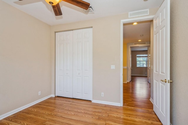 unfurnished bedroom featuring ceiling fan, light hardwood / wood-style floors, and a closet