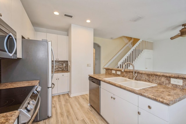 kitchen with sink, light hardwood / wood-style flooring, decorative backsplash, appliances with stainless steel finishes, and white cabinetry