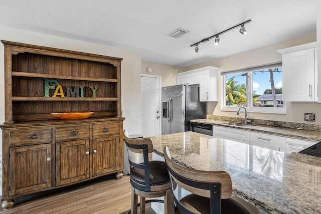 kitchen with light stone counters, stainless steel appliances, sink, light hardwood / wood-style flooring, and white cabinetry