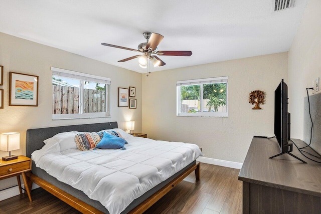 bedroom featuring multiple windows, dark hardwood / wood-style floors, and ceiling fan