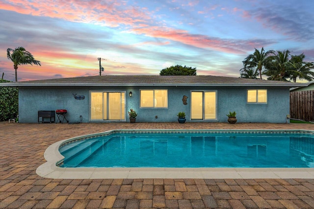 pool at dusk with a patio area