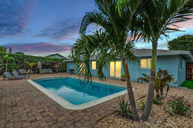 pool at dusk featuring a patio area