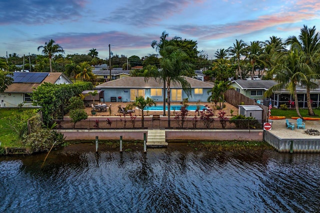 back house at dusk with a patio area and a water view