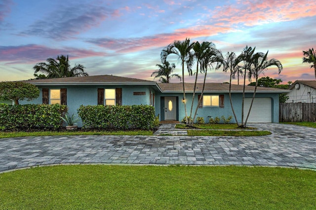 ranch-style home featuring a lawn and a garage