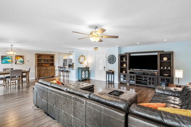 living room featuring hardwood / wood-style floors, ceiling fan, and a textured ceiling