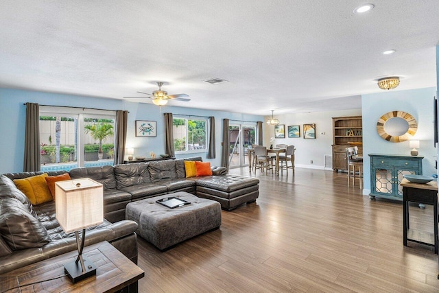 living room featuring hardwood / wood-style floors, ceiling fan, a healthy amount of sunlight, and a textured ceiling