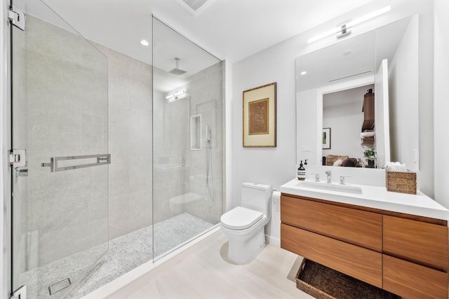 bathroom with tiled shower, vanity, and toilet