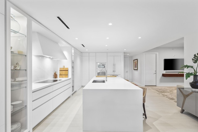 kitchen featuring sink, black electric stovetop, built in refrigerator, a breakfast bar, and white cabinets