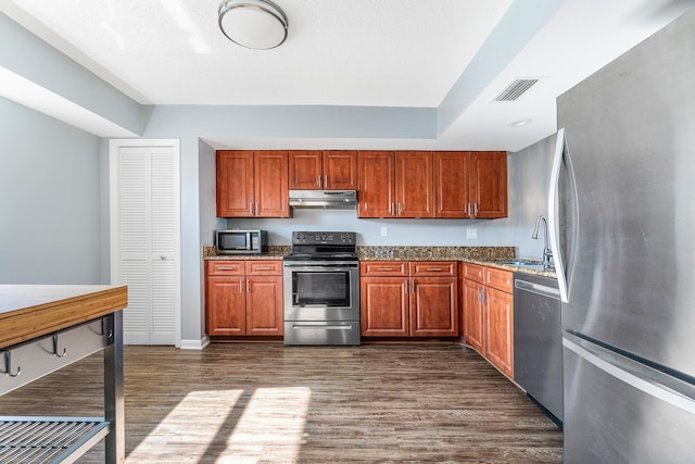 kitchen featuring visible vents, under cabinet range hood, dark wood-style floors, stainless steel appliances, and a sink