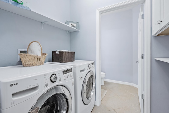 clothes washing area featuring washer and dryer, cabinets, and light tile patterned floors