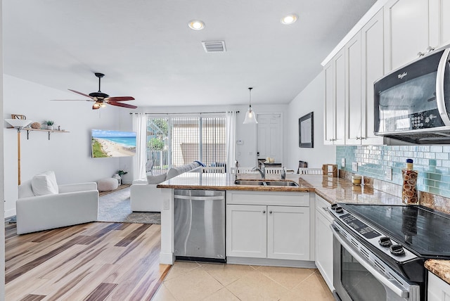 kitchen with stainless steel appliances, sink, decorative light fixtures, light hardwood / wood-style flooring, and white cabinets