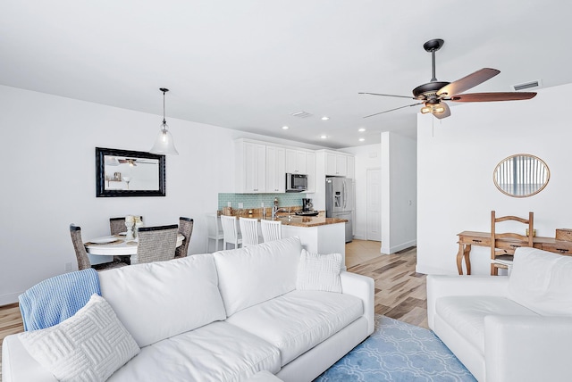 living room with light hardwood / wood-style flooring and ceiling fan