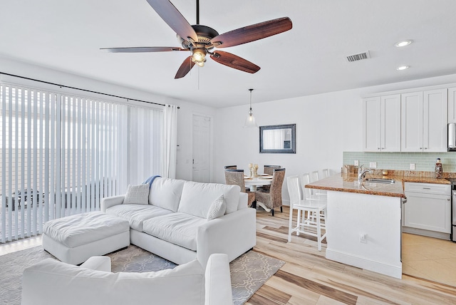 living room featuring ceiling fan, light hardwood / wood-style floors, and sink