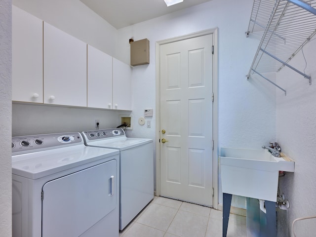 washroom with cabinets, light tile patterned floors, and washing machine and clothes dryer