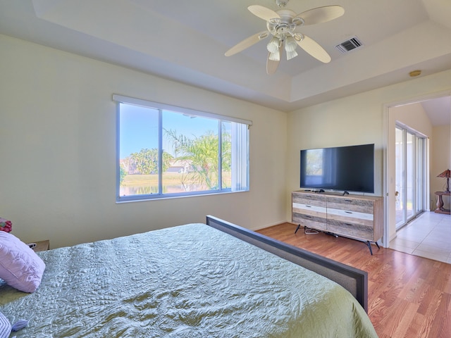 bedroom with a tray ceiling, ceiling fan, and wood-type flooring