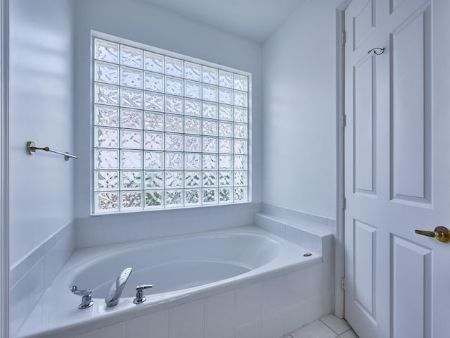 bathroom with a relaxing tiled tub and tile patterned floors