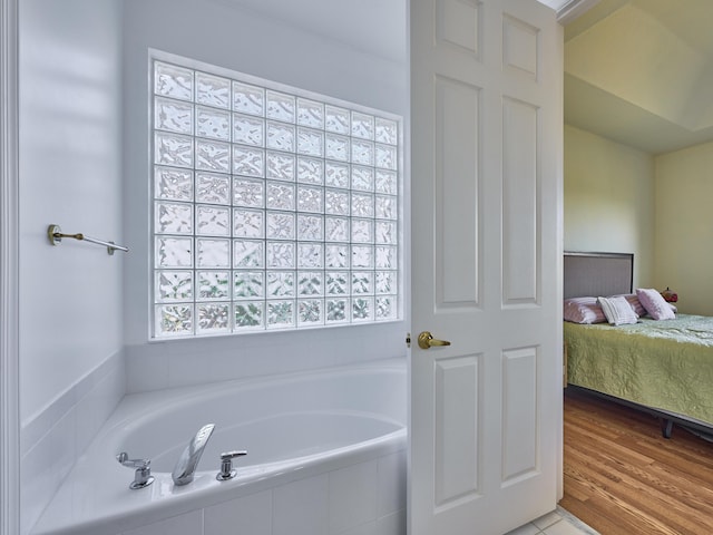 bathroom featuring hardwood / wood-style floors, plenty of natural light, and tiled tub