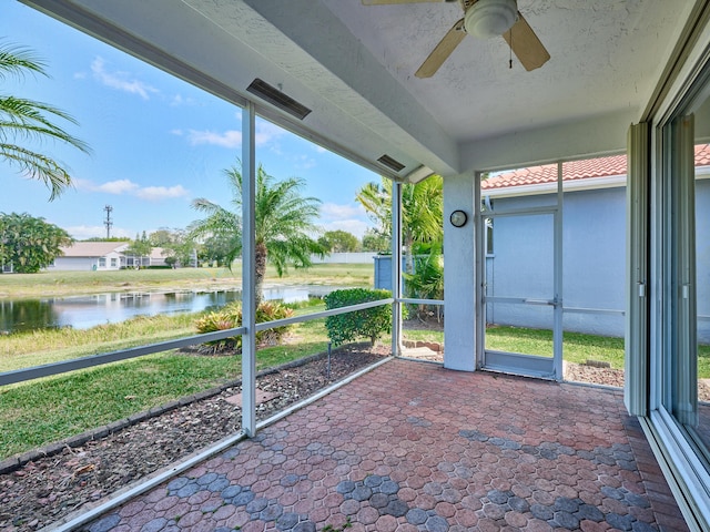 unfurnished sunroom featuring a wealth of natural light, ceiling fan, and a water view