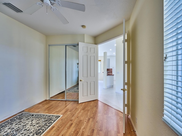 unfurnished bedroom featuring multiple windows, ceiling fan, a closet, and light hardwood / wood-style flooring