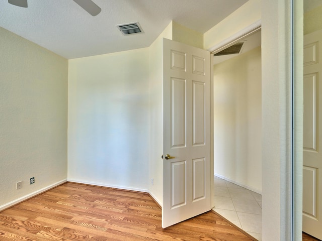 unfurnished room featuring ceiling fan, a textured ceiling, and light wood-type flooring