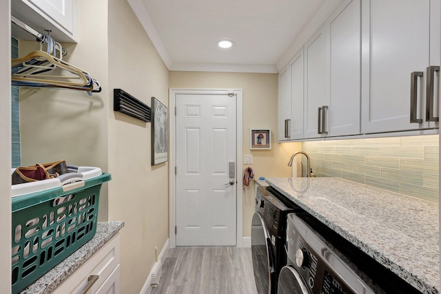 laundry room featuring independent washer and dryer, cabinet space, light wood-style floors, crown molding, and baseboards