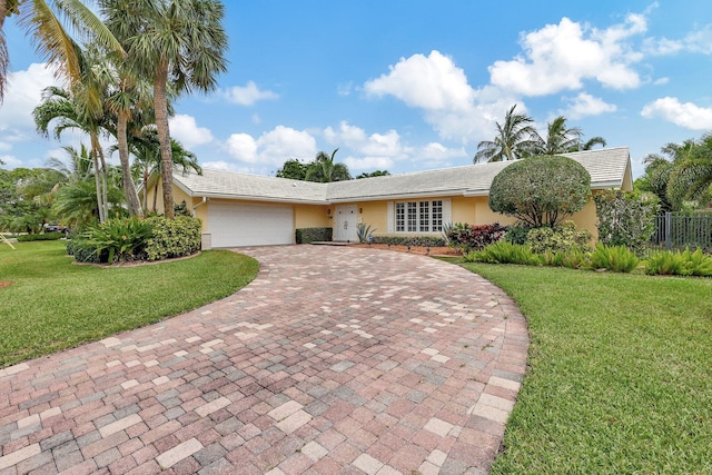 single story home featuring a front lawn, a tile roof, stucco siding, decorative driveway, and an attached garage