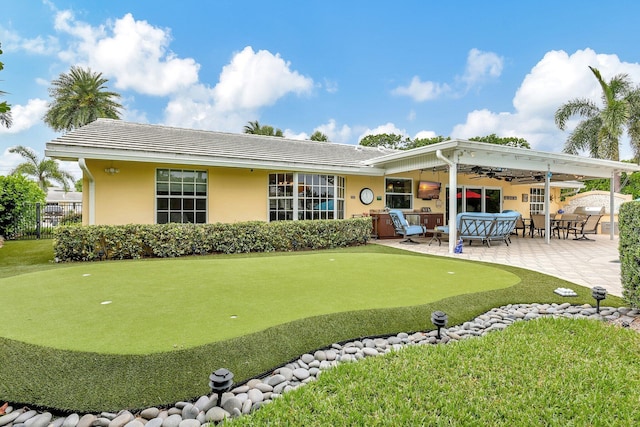 rear view of house featuring ceiling fan, fence, a tile roof, stucco siding, and a patio area