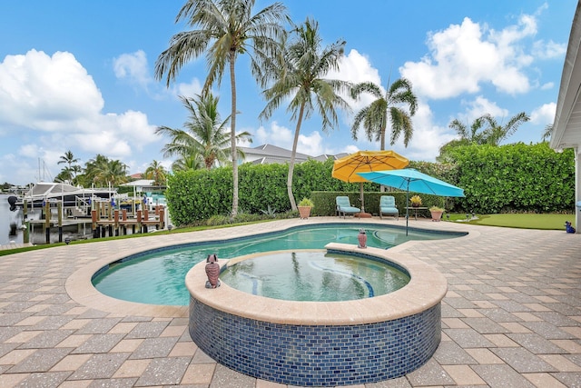 view of swimming pool featuring a boat dock, a pool with connected hot tub, and a patio