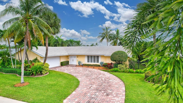 ranch-style home featuring decorative driveway, a front lawn, an attached garage, and stucco siding