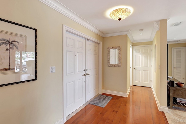 interior space with light wood finished floors, visible vents, crown molding, and baseboards