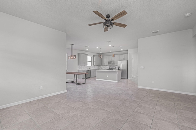 unfurnished living room featuring ceiling fan, light tile patterned floors, and a textured ceiling