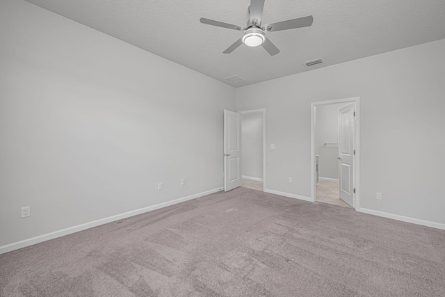 unfurnished bedroom with a textured ceiling, ceiling fan, and light carpet