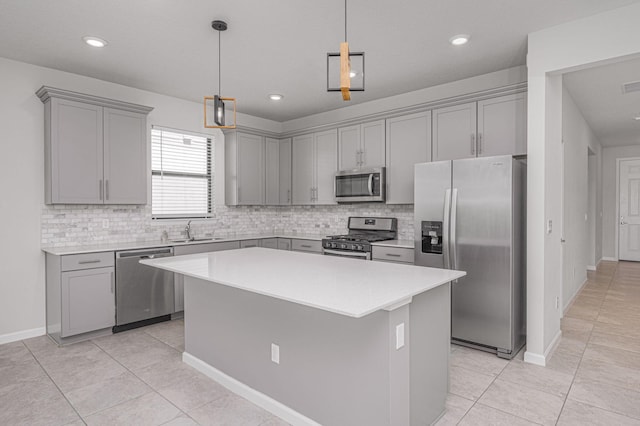 kitchen with pendant lighting, a center island, sink, gray cabinets, and appliances with stainless steel finishes