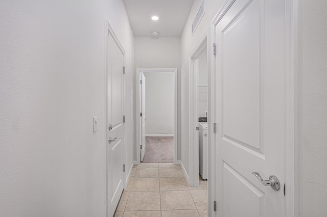 hall with washer / clothes dryer and light tile patterned floors