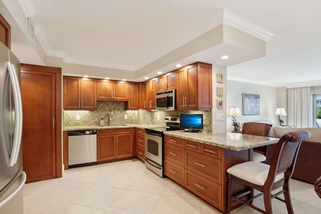 kitchen with light stone countertops, sink, kitchen peninsula, a kitchen bar, and appliances with stainless steel finishes