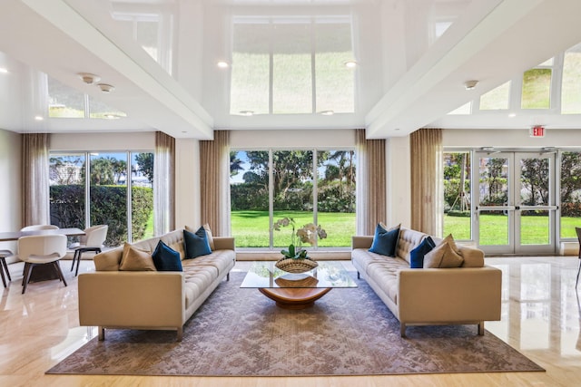 living room with french doors, a towering ceiling, and light wood-type flooring