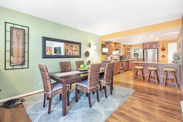 kitchen featuring tasteful backsplash, light stone counters, kitchen peninsula, light hardwood / wood-style floors, and appliances with stainless steel finishes