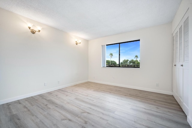 unfurnished room with a textured ceiling and light wood-type flooring