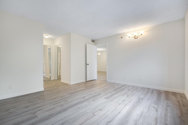 unfurnished room featuring light wood-type flooring and a textured ceiling