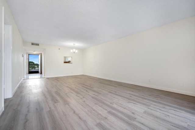 unfurnished living room featuring light wood-type flooring and a chandelier