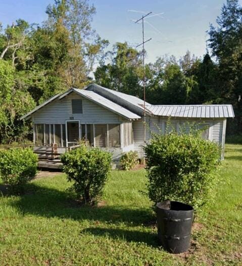 back of house featuring a wooden deck, a sunroom, and a yard