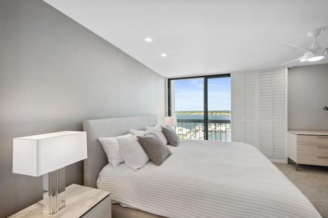 carpeted bedroom with access to outside, ceiling fan, and a water view