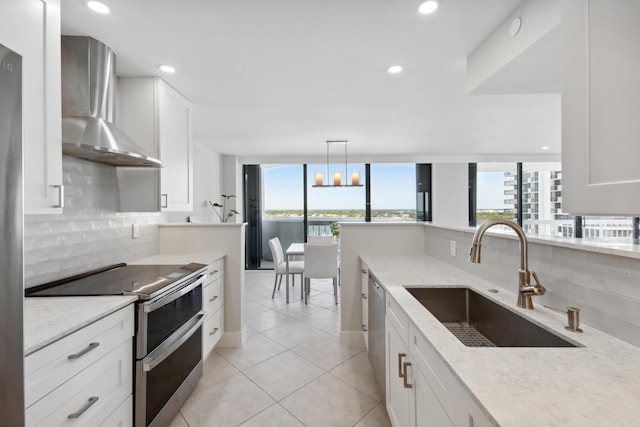 kitchen featuring white cabinetry, sink, wall chimney range hood, decorative backsplash, and appliances with stainless steel finishes