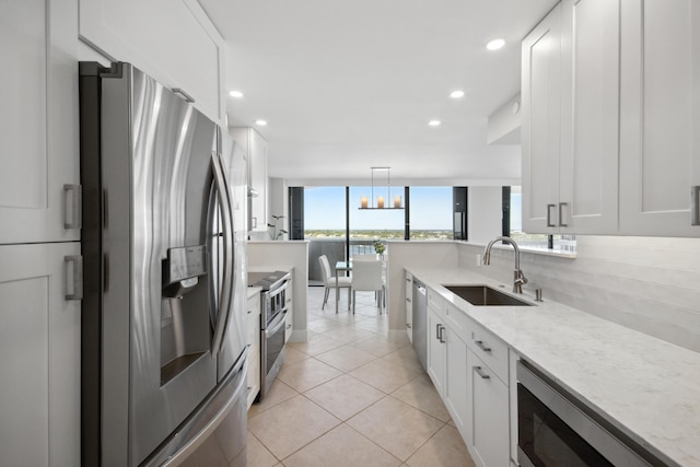 kitchen featuring decorative light fixtures, sink, white cabinetry, and stainless steel appliances