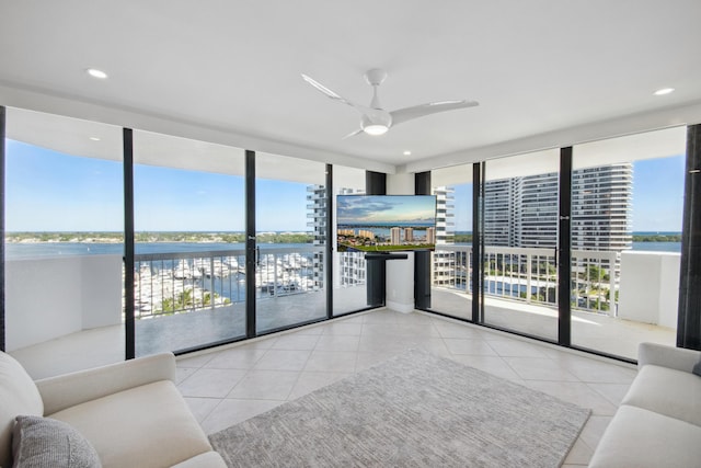 tiled living room with expansive windows, a water view, and ceiling fan