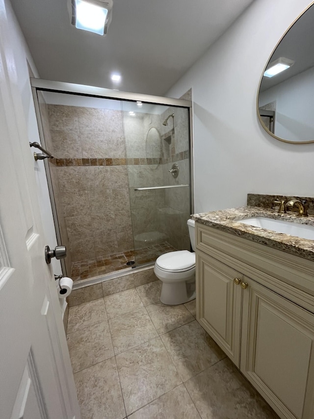 bathroom with tile patterned floors, vanity, an enclosed shower, and toilet