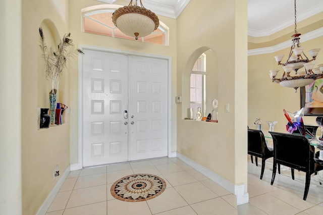 tiled foyer with ornamental molding, a high ceiling, and an inviting chandelier